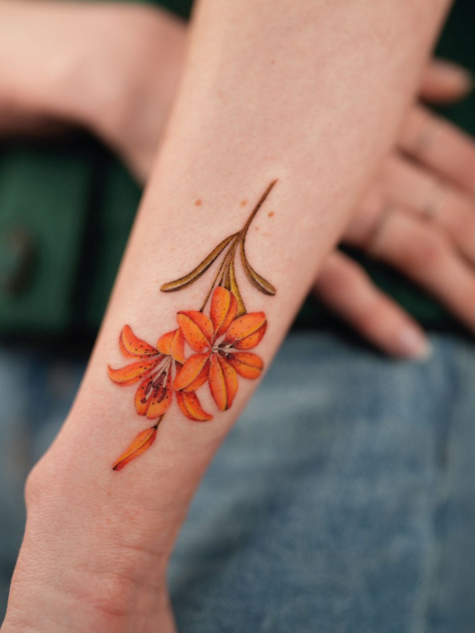 tatouage d'une fleur en couleur sur un avant bras
